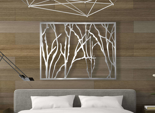 White abstract wall art with tree branch shapes above a bed with pillows